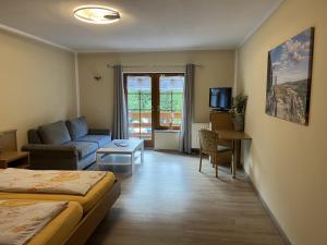 a room with a bed and a couch and a table at Pension Ostrauer Mühle in Bad Schandau