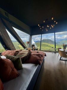 a bedroom with a large bed in a room with large windows at Eagle Nest Eco Lodge in Sel