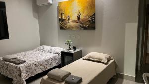 een slaapkamer met twee bedden en een schilderij aan de muur bij Casa Cobogó - 5min da Granja e da ANP in Brasilia