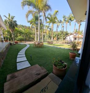 a walkway in a park with palm trees and tables at Villa Pomerode Hospedagem - Suítes com conforto e aconchego conectados com a Natureza in Pomerode +20 photos