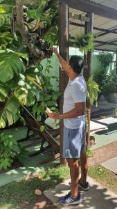 a man is reaching up to touch a plant at Enjoy suítes in Aracaju