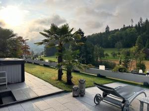 a black chair on a patio with a palm tree at Residenza San Remy Hundefreundliche Ferienwohnung mit Whirlpool in Unterkulm