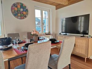 a dining room with a table with chairs and a television at Frutigen 20 nach Interlaken in Frutigen