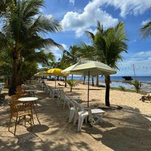 a row of tables and chairs on a beach with palm trees at Gold View Beachfront Resort in Timbaon