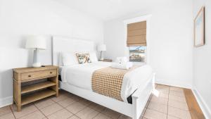 a white bedroom with a bed and a window at 5BR plus Den - Downtown OC - Sleeps 16 in Ocean City