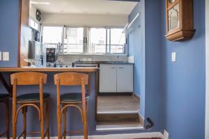 a kitchen with blue walls and two stools at a counter at Departamento hasta 7 personas en Recoleta in Buenos Aires