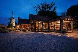 ein Haus mit einer Windmühle im Hintergrund in der Unterkunft Guesthouse Ensenada in Schoondijke