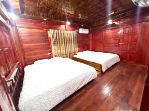two beds in a small room with wood paneling at Moc Chau Town - Homestay in Mộc Châu