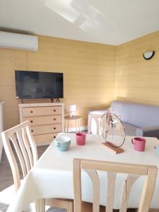 een woonkamer met een tafel en stoelen en een televisie bij Les Hauts de Balaruc- Idéal Curistes 102 in Balaruc-les-Bains