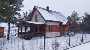 a small house with a fence in the snow at Dom nad jeziorem Serwy in Serwy