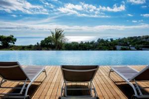 two chairs sitting on a deck next to a swimming pool at The View Mauritius in Ruisseau Créole