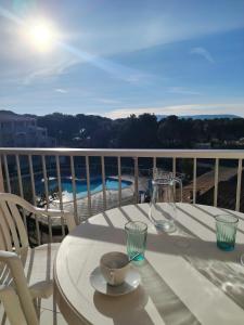 een witte tafel met een kom en glazen op een balkon bij Les Hauts de Balaruc- Idéal Curistes 102 in Balaruc-les-Bains +5 foto's