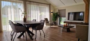 a living room with a table and chairs and a television at Vakantievilla de Broak in Ambt Delden