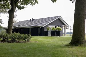 a black house with a tree in front of it at Vakantievilla de Broak in Ambt Delden