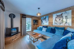 a living room with a blue couch and a tv at Le Chalet 138 Megève séjour pour 8 confort espace charme calme in Demi-Quartier