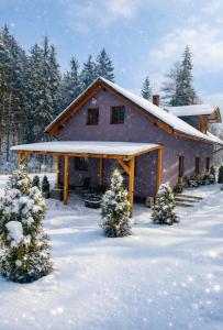 a house with a snow covered roof in the snow at Casa NICOLE in Malá Morávka