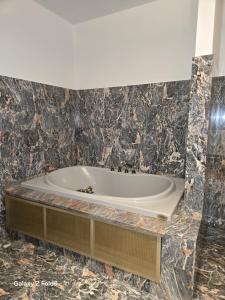 een badkuip in een badkamer met zwart marmer bij Villa Trigatti 