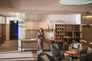 a woman standing at a counter in a room with chairs at Residence Sovara in Santa Cristina in Val Gardena