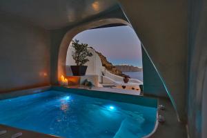 a swimming pool in a house with a window at Blue Art Caves in Oia