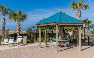 a gazebo with chairs and a table and palm trees at Phoenix East II 2032 in Orange Beach