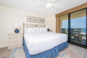 a bedroom with a large white bed and a balcony at Phoenix East II 2033 in Orange Beach