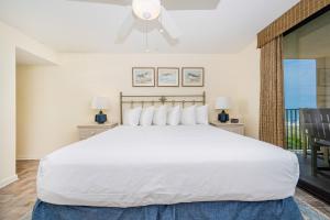 a bedroom with a large white bed and a balcony at Phoenix East II 2033 in Orange Beach +63 photos