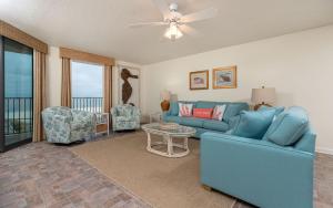 a living room with a blue couch and chairs at Phoenix East II 2033 in Orange Beach