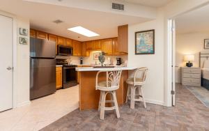 a kitchen with a refrigerator and two bar stools at Phoenix East II 2033 in Orange Beach