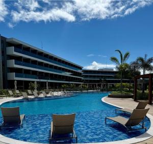 a swimming pool with lounge chairs and a building at Beach Class Summer Residence in Ipojuca