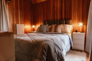 a bedroom with a large bed with wooden walls at Cabañas Punto Prana in Tandil