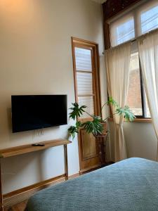a bedroom with a flat screen tv on a wall at Hostal Dinamarca in Valparaíso