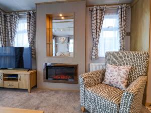 a living room with a chair and a tv at Paws By The Sea in Norwich