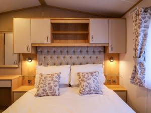 a bedroom with a white bed with cabinets and pillows at Paws By The Sea in Norwich