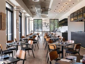 a dining room with tables and chairs and windows at Mantra MacArthur Hotel in Canberra
