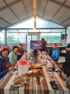 a group of people sitting around a long table with food at Chaullay Star Domes in Colcapampa