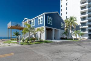 a blue house with palm trees in front of a building at Punta Rassa Pointe by Sun Palace Vacations in Fort Myers