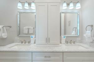 a white bathroom with two sinks and two mirrors at Punta Rassa Pointe by Sun Palace Vacations in Fort Myers +31 photos