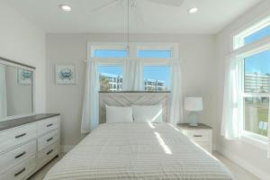 a white bedroom with a bed and two windows at Punta Rassa Pointe by Sun Palace Vacations in Fort Myers