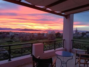 a sunset from a balcony with a table and chairs at The house of joy in Egina