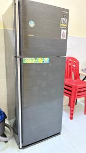 een roestvrijstalen koelkast in een keuken met een rode stoel bij Homestay Tanjung Malim DMalim in TanjongMalim