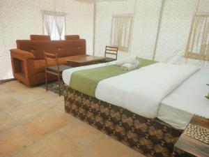 a bedroom with a large bed and a chair at Raj Kesari Heritage Camp in Jaisalmer