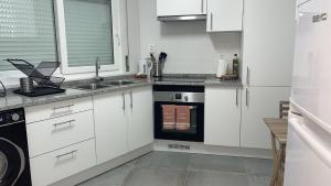 een witte keuken met een spoelbak en een fornuis bij Casa Rosa in Parede