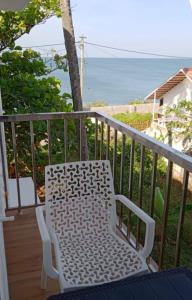 een witte stoel op een balkon met uitzicht op de oceaan bij Hilton Hill in Varkala