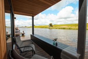 een veranda met twee stoelen op een boot op een rivier bij Tiny Boat House #3 in Garnwerd