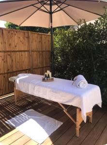 a table sitting under an umbrella on a deck at Lodge Valbelle, maison indépendante avec jacuzzi, Love room in Tourves