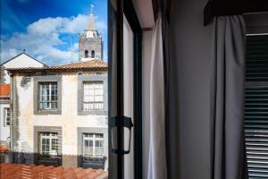 a window with a view of a building with a tower at Murças74 - Studio Apartments in Funchal +33 photos