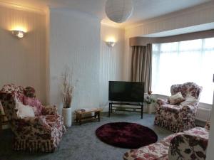 a living room with two chairs and a flat screen tv at Beautiful 'Rose-Dene' with ample parking in Sheerness