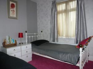 a bedroom with a bed and a dresser and a window at Beautiful 'Rose-Dene' with ample parking in Sheerness