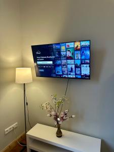 una TV su un muro sopra un tavolo con fiori di Elegantes Innenstadt Apartment a Brema