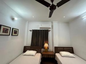 two beds in a room with a ceiling fan at Junput Guest House in Bichania
